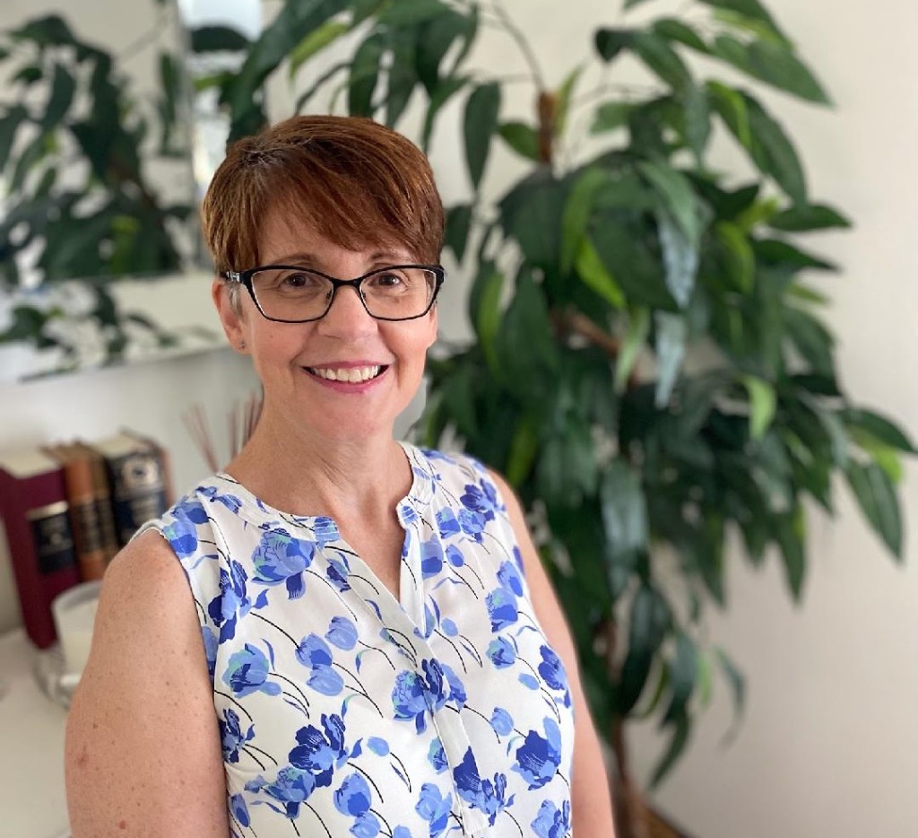 Kelly Babinski, CRNP, smiling in a blue floral blouse